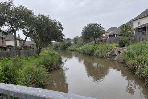 Houses on both banks of a tree-lined creek in a suburban neighborhood