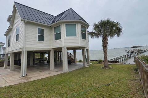 Standing-seam metal panels on a raised bayfront house with water visible beyond