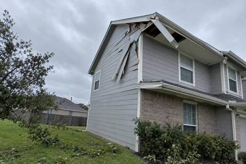Section of siding and fascia torn loose at a gable corner after strong wind